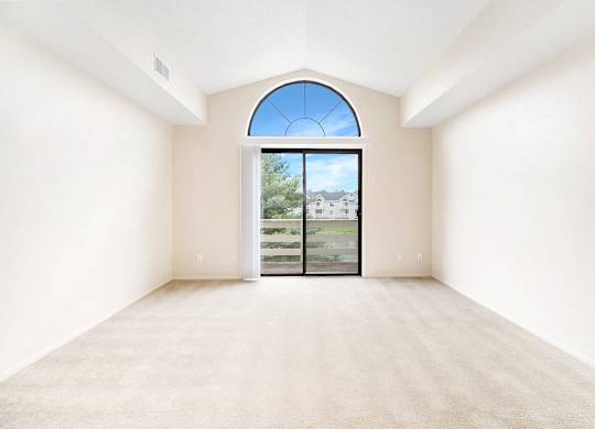 A living room with a large window and a high ceiling at Arbor Lakes Apartments in Elkhart, IN