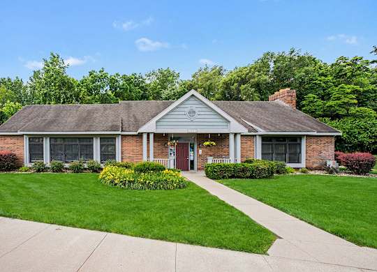A leasing office and clubhouse with a red door and a small porch at Arbor Lakes Apartments in Elkhart, IN