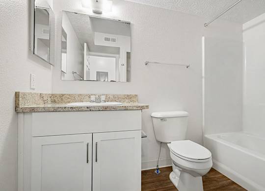 A white bathroom with a mirror, toilet and bathtub at Autumn Lakes Apartments and Townhomes, Mishawaka, 46544