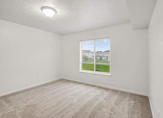 A spacious bedroom with a carpeted floor and a window at Autumn Lakes Apartments and Townhomes, Mishawaka, 46544