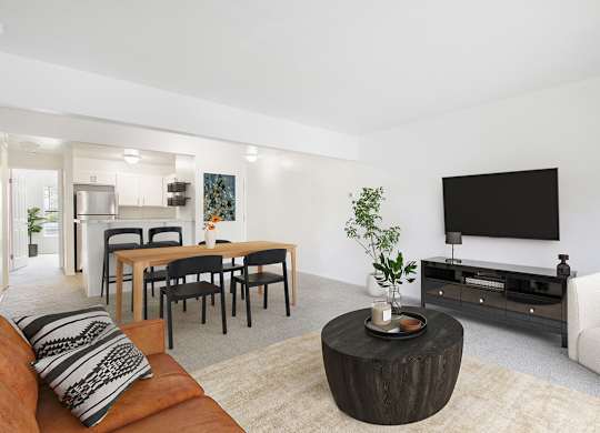 A living room with a brown couch, a wooden coffee table, and a flat screen TV mounted on the wall at Autumn Lakes Apartments and Townhomes, Mishawaka, 46544