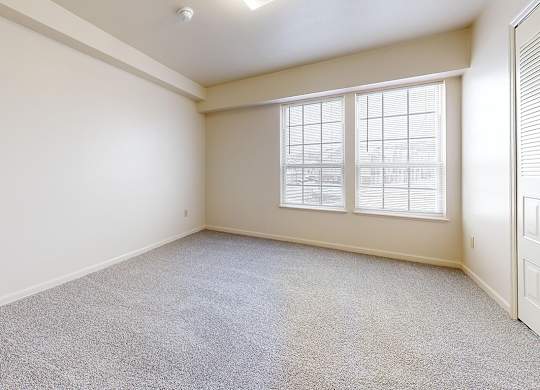 A bedroom with a carpeted floor and a window with blinds at Autumn Lakes Apartments and Townhomes in Mishawaka, IN