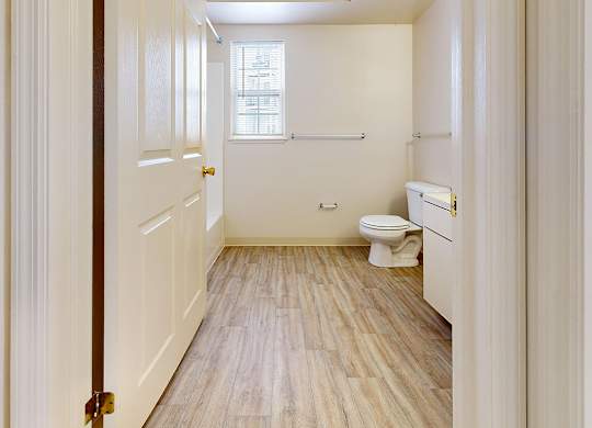 A white bathroom with a toilet, sink, and window at Autumn Lakes Apartments and Townhomes in Mishawaka, IN