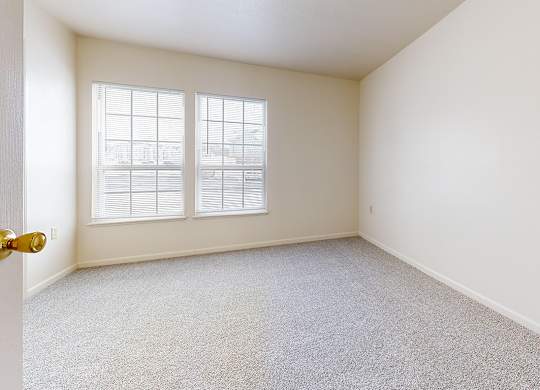 A bedroom with a carpeted floor and a large window at Autumn Lakes Apartments and Townhomes in Mishawaka, IN