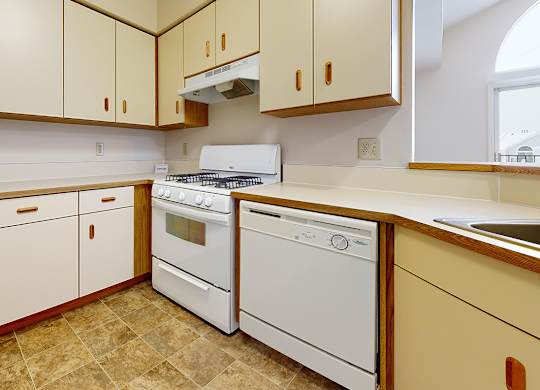 A kitchen with white appliances and wooden cabinets at Autumn Lakes Apartments and Townhomes in Mishawaka, IN