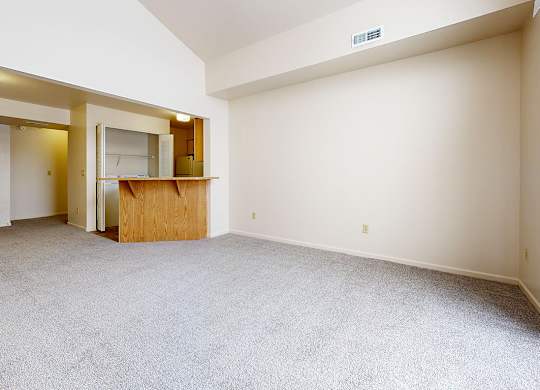 A living and dining room with a carpeted floor and a cathedral ceiling at Autumn Lakes Apartments and Townhomes in Mishawaka, IN