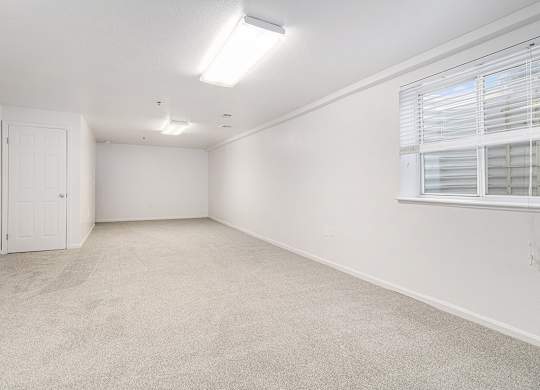 A finished basement recreation room with a carpeted floor and a window with blinds at Autumn Lakes Apartments and Townhomes, Mishawaka, 46544