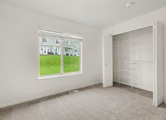A bedroom with a large window and walk-in closet with organizers at Autumn Lakes Apartments and Townhomes, Mishawaka, 46544