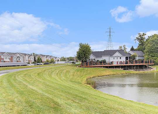 A grassy area with a pond and buildings in the background at Autumn Lakes Apartments and Townhomes, Mishawaka, IN
