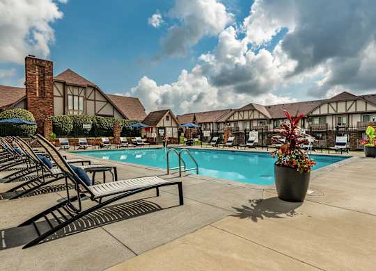 A pool area with sun loungers and a building in the background