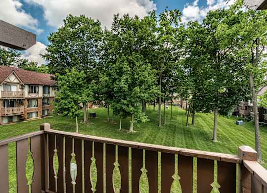 A balcony overlooks a grassy area with trees