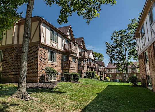 A tree stands in front of a building with a lawn in front of it at Autumn Woods Apartments, Miamisburg
