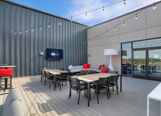 a rooftop patio area with tables and chairs and a tv in Carmel, IN