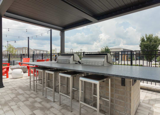 Grilling stations with chairs on a patio at Avant Apartments in Carmel, IN, 46032