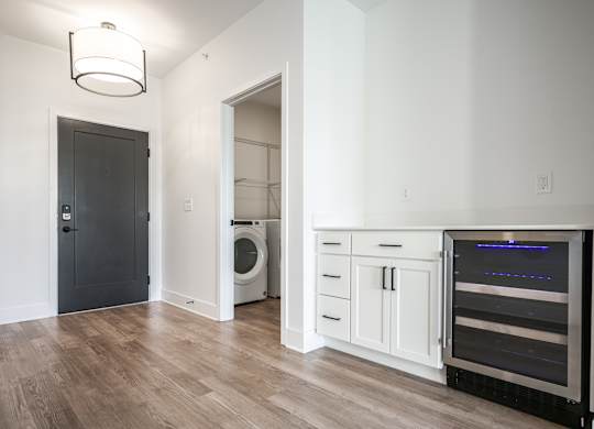 a living room with a washer and dryer and a door to a bathroom at Avant & Avant II, Carmel, IN, 46032
