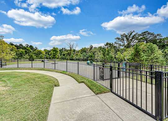 a park with a black fence and a sidewalk and grass at Avellan Springs Apartments, Morrisville, NC
