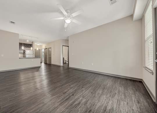 the living room and kitchen of a new home with white walls and wood floors at Avellan Springs Apartments, Morrisville, NC