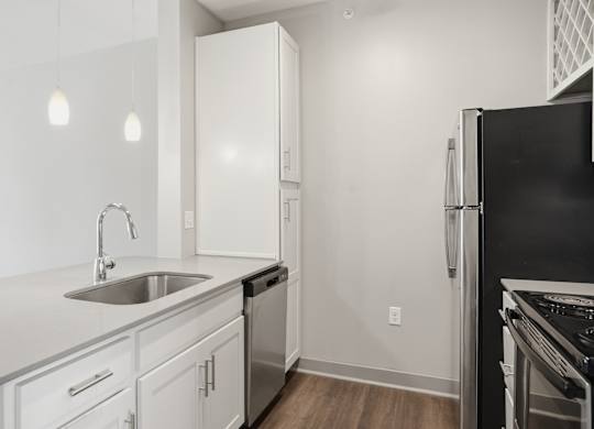 A modern kitchen with white cabinets and a black refrigerator.