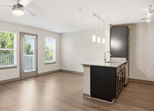 A kitchen area with a black fridge and a ceiling fan.