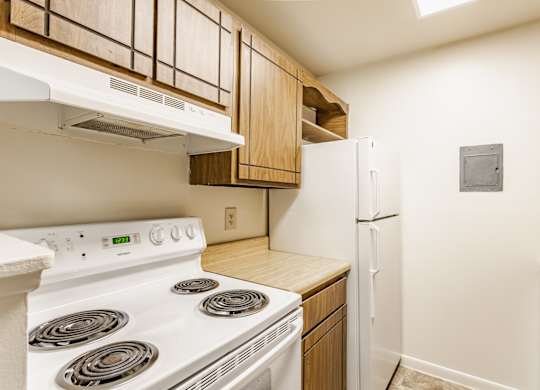 A white stove and refrigerator in a kitchen with wooden cabinets