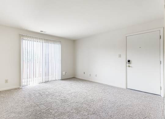 A room with a carpeted floor and a sliding glass door