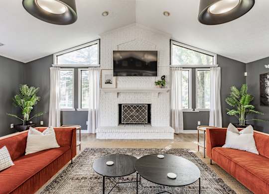 A living room with a fireplace and a television mounted above it