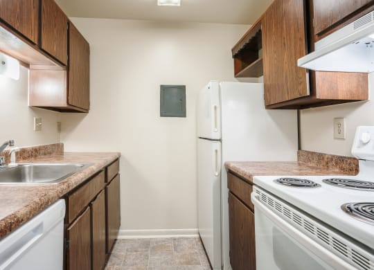 a kitchen with white appliances and wooden cabinets and a white refrigerator at Bavarian Village Apartments, Indianapolis, IN