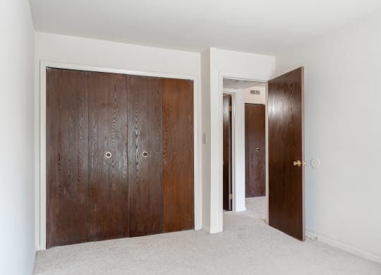 a room with two wooden doors and a carpeted floor at Bavarian Village Apartments, Indianapolis, IN
