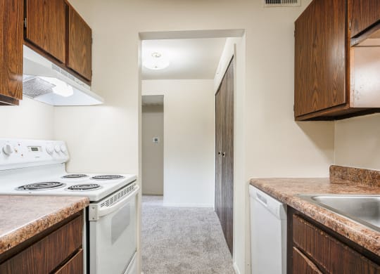 a kitchen with white appliances and wooden cabinets and a white stove top oven at Bavarian Village Apartments, Indianapolis, IN