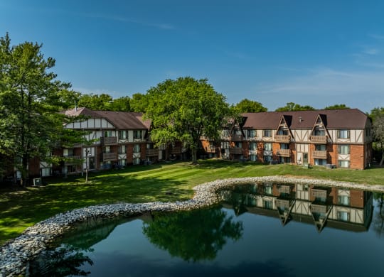 an apartment complex with a pond in front of it