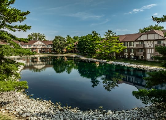 a large pond in front of a building with trees