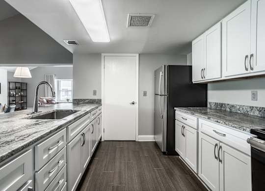 A modern kitchen with white cabinets and a black refrigerator.