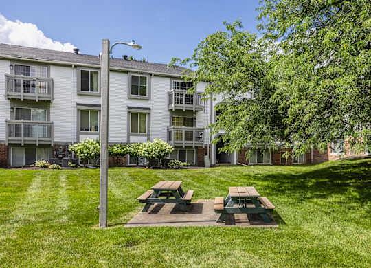 A grassy area with a picnic table in front of a building.