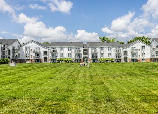 A row of white apartment buildings with green lawns in front.