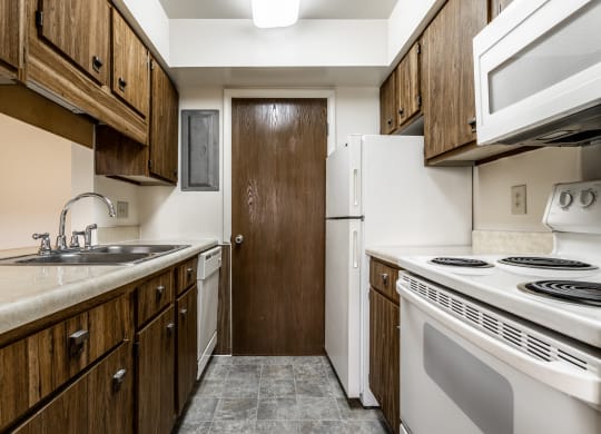 a kitchen with white appliances and wooden cabinets and a refrigerator at Bay Pointe Apartments in Indiana 47909