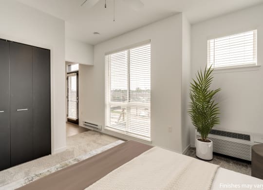 a bedroom with a large window and a large potted plant  at Uptown Square Apartments, Michigan, 48083
