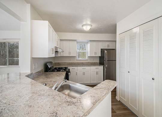 A kitchen with white cabinets and a breakfast bar at Black Sand Apartment Homes in Lincoln, NE