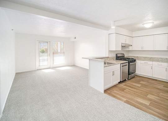 an upgraded kitchen and living room with white cabinets at Black Sand Apartment Homes in Lincoln, NE