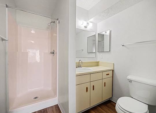 A white bathroom with a toilet, sink, and shower at Brentwood Park Apartments in LaVista, NE