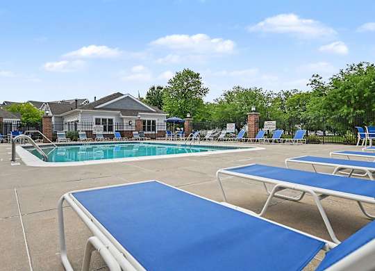 A sunny day at the pool with blue loungers and a building in the background at Brentwood Park Apartments in LaVista, NE