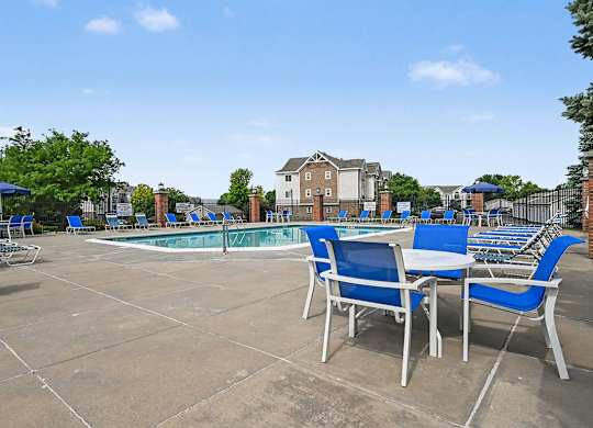 A pool area with blue chairs and a table at Brentwood Park Apartments in LaVista, NE