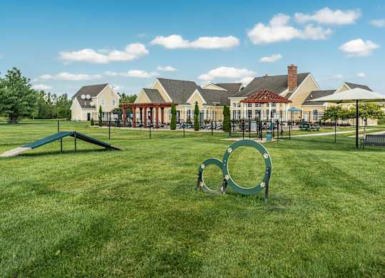 A playground with a green swing set and a large metal ring in the foreground