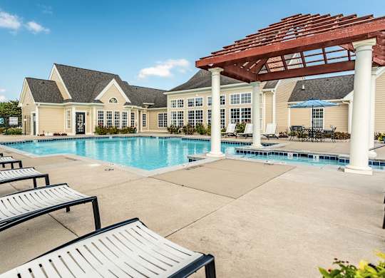 A pool area with sun loungers and a pavilion