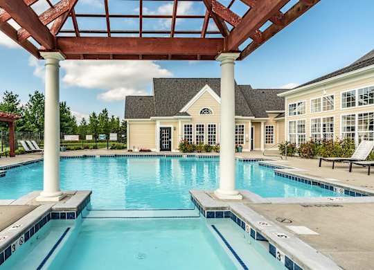 A large swimming pool with a wooden pergola over it