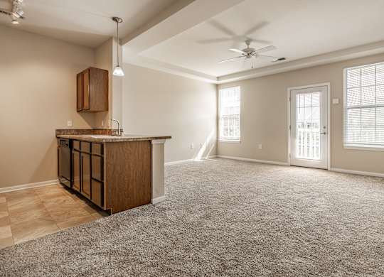 A spacious living room with a carpeted floor and a ceiling fan