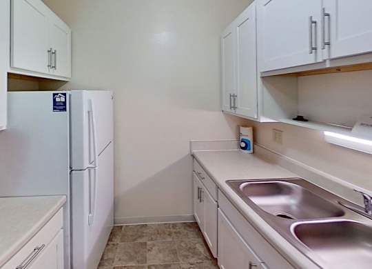 a kitchen with white cabinets and a sink and a refrigerator at Briarwood Apartments, Benton Harbor, 49022