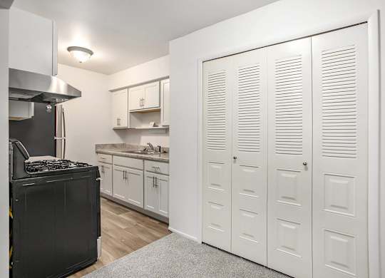 A kitchen with white cabinets and a large closet at Brookside Apartments, Springfield