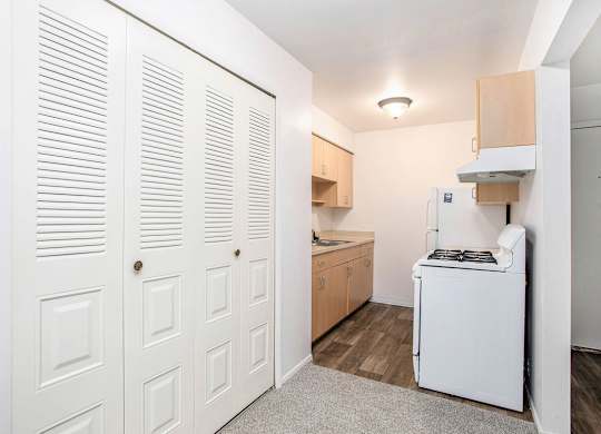 A galley kitchen with white appliances and a closet at Brookside Apartments, Springfield