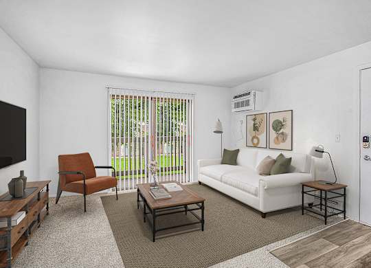 A living room with a white couch, a brown chair, and sliding glass doors to a balcony at Brookside Apartments, Springfield