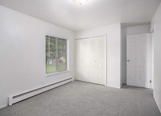 A bedroom with a window with blinds and a closet at Brookside Apartments, Springfield